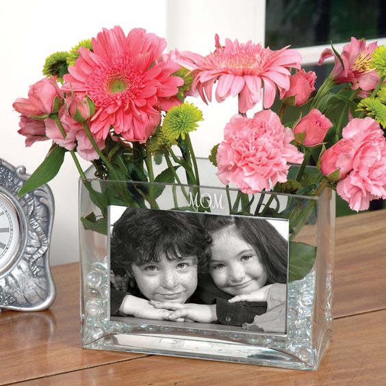 a glass vase with a kids' photo and pink flowers