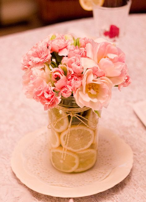 a jar filled with lemon slices and blush and pink flowers
