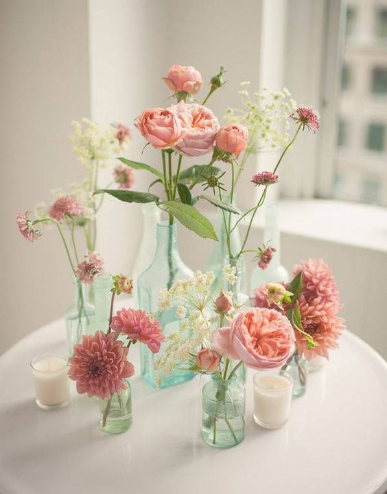 simple pink flower arrangement in different bottles and vases