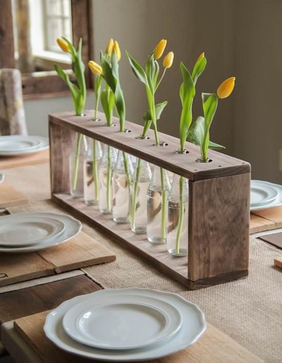a frame of repurposed pallets with bottles and single tulips in each