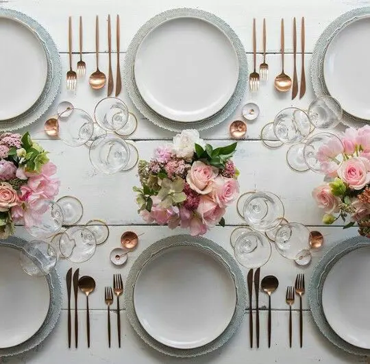 the tablescape is neutral but with pink centerpieces and glam gold cutlery