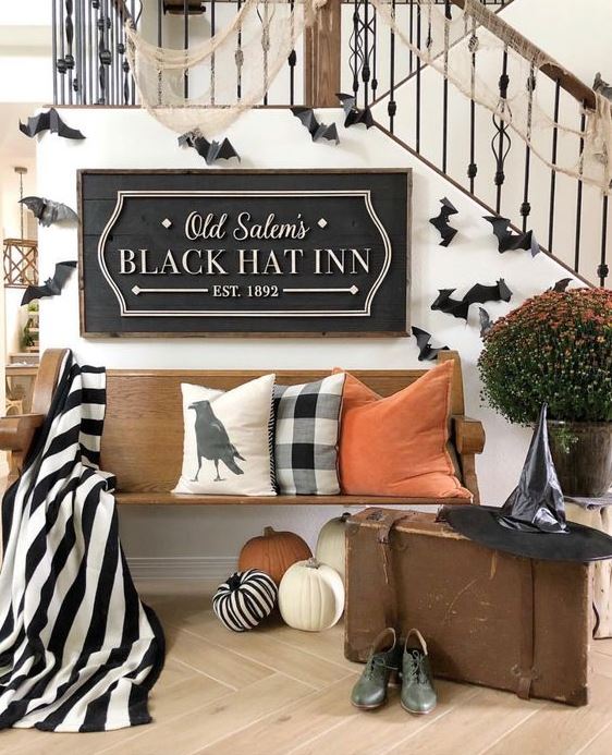 a classic Halloween entryway with printed and orange textiles, bats, web and a witch hat and shoes
