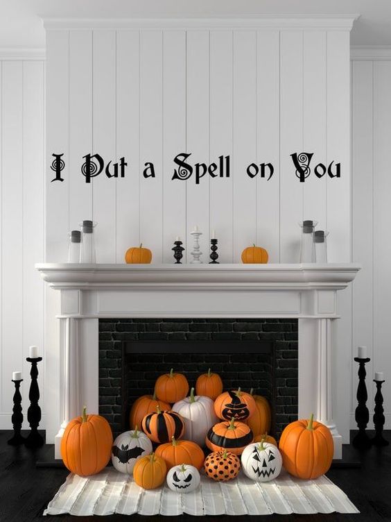a classic Halloween fireplace with orange, black and white pumpkins, letters and candles is chic