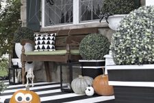 a classic black and white Halloween porch with pumpkins, scary heads, spiders and spider web