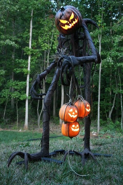 a giant Halloween reaper with a pumpkin lantern head and some adidtional lanterns in his hands is a scary statement for outdoors