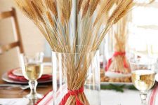a glass with wheat and a red ribbon placed on a tray with nuts is a cool fall to winter centerpiece