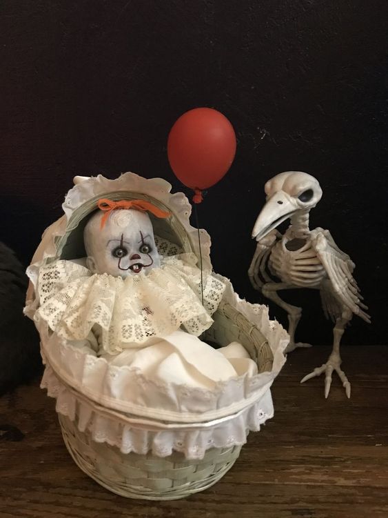 a spooky Halloween decoration of a raven skeleton and a baby in a crib with a red balloon inspired by the It