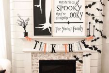 chic black, white and orange mantel styling with bats, a bright bunting, Halloween signs and pumpkin stacks