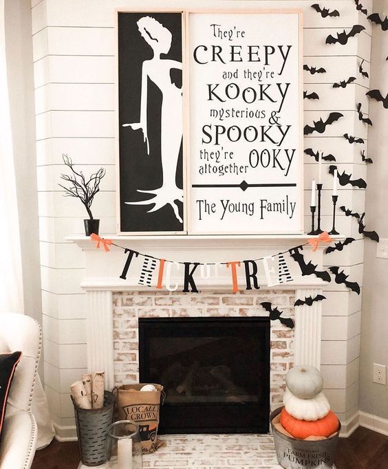 chic black, white and orange mantel styling with bats, a bright bunting, Halloween signs and pumpkin stacks