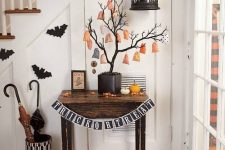 classic Halloween decor with bats, pumpkins and a Halloween tree with favors hanging on it