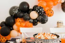 classic bright Halloween styling with fun plates, candy corn in a bowl and a large orange and black balloon garland