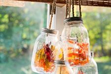 glasses with dried blooms, fall leaves and berries hanging over the space are a cool decoration in rustic style