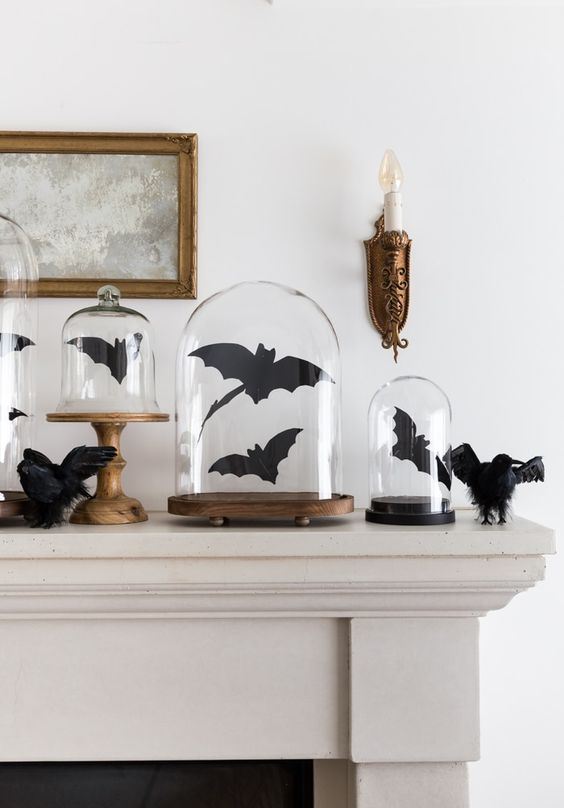 mantel decor with black bats in cloches and blackbirds is a cool and classic idea to style for Halloween
