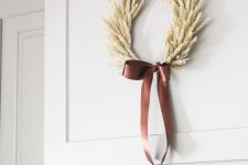 a stylish and laconic wheat fall wreath with a large brown silk bow for a contrasting accent