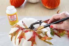 a white pumpkin with colorful fall leaves attached is a nice and simple fall decoration