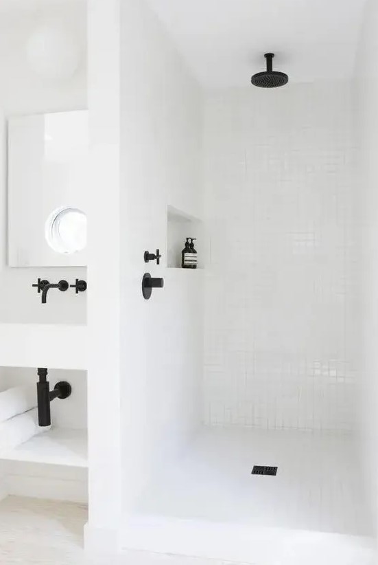 a contemporary white bathroom clad with square tiles and black fixtures, a niche shelf, a wall-mounted vanity is stylish