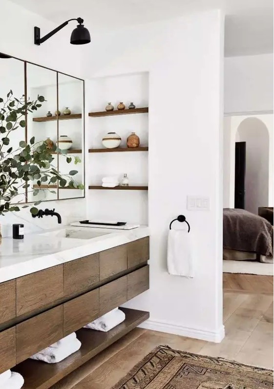 a modern farmhouse bathroom with a timber floating vanity and a shelf, with a niche with shelves for decor and a large mirror