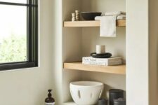 a neutral bathroom with a niche with wooden shelves used for placing decor there to make the bathroom look cooler