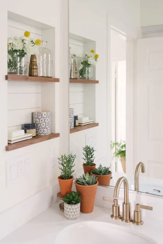 a neutral modern farmhouse bathroom with shiplap walls, a niche with shelves used for decor, potted plants and succulents