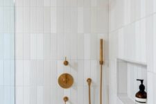 a neutral shower space clad with skinny tiles, with a niche for storage and brass fixtures is a cool and chic solution