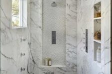 a shower space clad with marble tiles, with niches used for storing things that are necessary for washing, a window for natural light