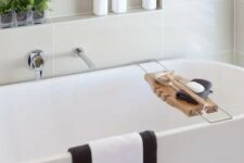 a stylish modern bathroom with an oval tub and a niche shelf over it, with decor and some bathroom stuff