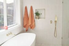 an airy modern bathroom with a shower space, an oval tub, a terrazzo floor, a skinny tile wall and a niche for decor