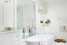 a contemporary bathroom in neutrals, with an oval tub, a large mirror and a double vanity plus lamps