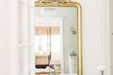 a vintage bathroom with molding, a navy bathtub, a crystal chandelier and a mirror in a gold ornate frame