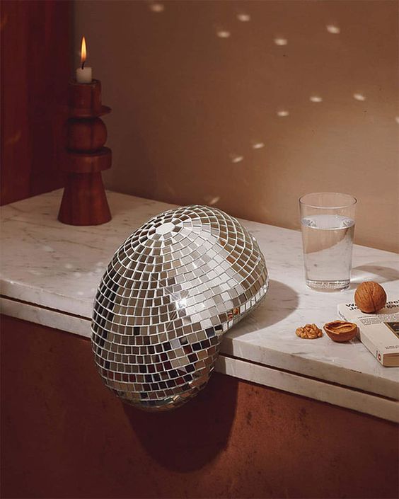 a fireplace decorated with a melting disco ball looks very col, bold and surrealistic adding interest to the space