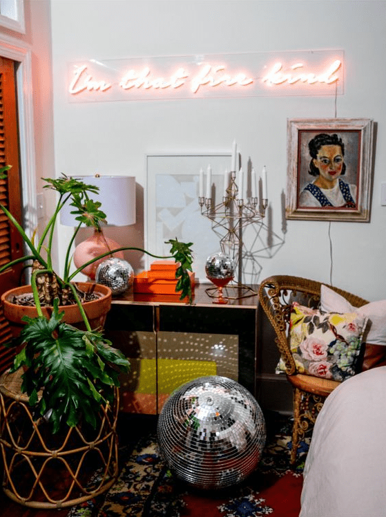 bright and whimsical decor with a credenza, a candelabra, a neon sign, a disco ball and a potted plant plus bright pillows