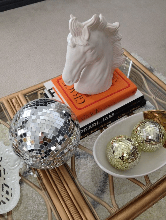 coffee table decor with a large silver disco ball and smaller gold ones, coffee table books and a horse head on top is amazing