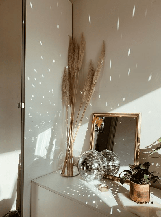 modern boho home decor with a mirror, a disco ball, pampas grass and a potted plant is a nice combo for any space