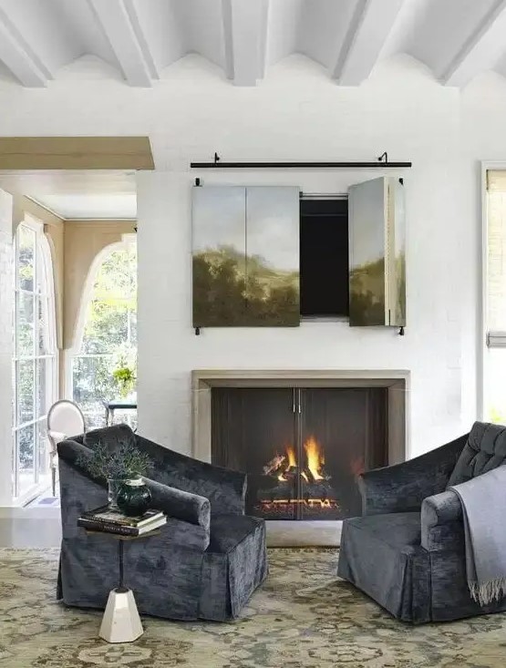 a cozy sitting nook with a real fireplace with a metal screen and a TV hidden behind an artwork that can be folded to watch TV