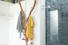a creative bathroom hanger and holder made of some tree branches and hooks attached to them