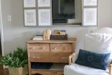 a farmhouse living room with vintage furniture, a reclaimed wooden vanity, a TV hidden behind a vintage poster gallery wall