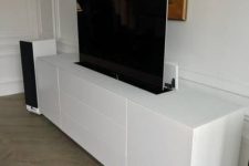 a sleek white media console hiding a TV – a smart TV lifting unit is a super cool solution to keep the space sleek