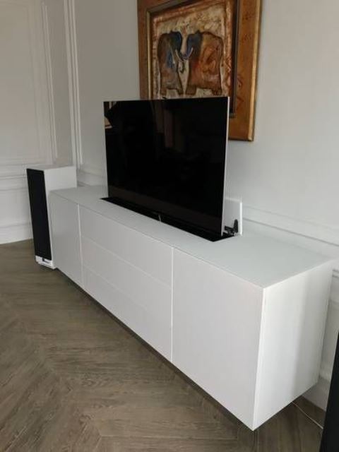 a sleek white media console hiding a TV - a smart TV lifting unit is a super cool solution to keep the space sleek