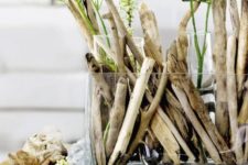 a spring centerpiece of driftwood, test tubes with white blooms looks super natural and very chic