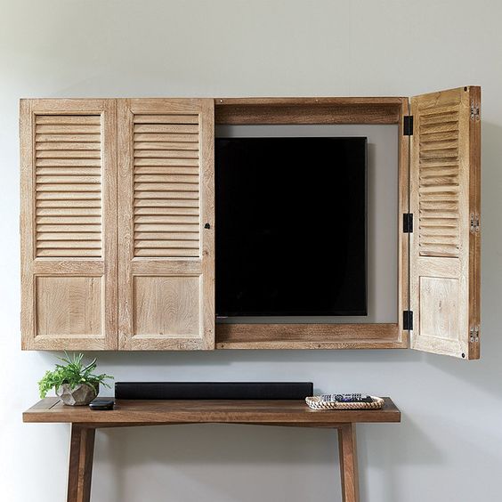 hand crafted shutter doors create the feeling of a window open and hide a wall-mounted TV at the same time adding a rustic feel to the interior