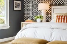 a dark bedroom refreshed with a monochromatic graphic accent wall and mustard stools upholstered with fabric