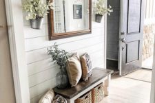 a neutral farmhouse entryway wiht a wooden bench and wicker cubbies plus a basket for storage