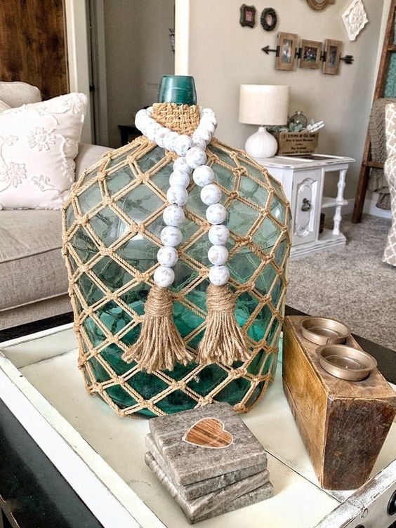 a green bottle with a twine net and whitewashed wooden beads is a cool decoration for a modern space
