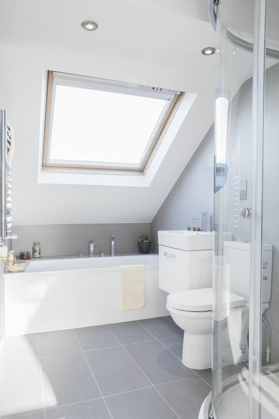 a laconic contemporary bathroom with grey tiles, a skylight, white appliances and built in lights