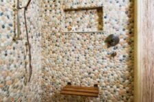 a shower space completely covered with pebbles of various muted colors looks very welcoming