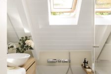 a tiny neutral bathroom with white and tan tiles, a skylight, wooden furniture and white appliances looks chic