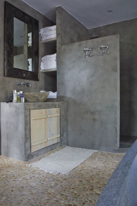 a wabi-sabi bathroom done with concrete and a pebble floor plus a stone sink is a bold and catchy idea