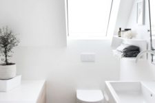an attic Scandinavian bathroom in white, with stained wooden floor, white appliances and a skylight is airy and serene