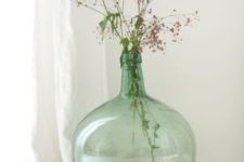 an oversized green bottle with pink blooms brings a fresh and bright feel to any space