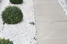 white pebbles covering the greenery growing and stone paths create a serene and polish outdoor look